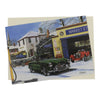 Aston Martin Christmas card features a classic green Aston DB3 on a snowy old garage forecourt with a red vintage car, a vintage motorcycle, and a Land Rover in the background
