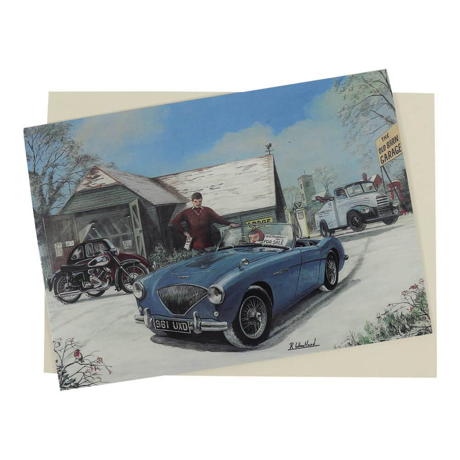 This traditional style Austin Healey Christmas card features a blue Healey 100 on a wintery snow-covered period garage forecourt setting.