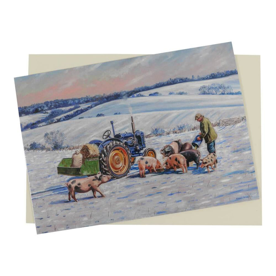 This scenic Fordson Christmas card features a blue Fordson tractor in a snow-covered field surrounded by pigs being fed by the farmer.